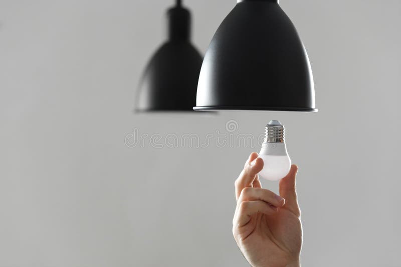 Changement de l'ampoule pour l'ampoule menée dans le lampadaire dans la couleur noire Sur le fond gris-clair photos stock Changement de l'ampoule pour l'ampoule menée dans le lampadaire dans la couleur noire Sur le fond gris-clair photos stock