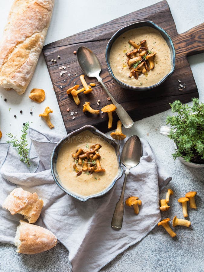 Chanterelle cream soup in blue bowls and baguette on the rustic table and wood board. royalty free stock photography Chanterelle cream soup in blue bowls and baguette on the rustic table and wood board. royalty free stock photography