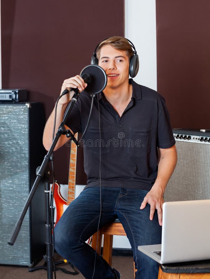 Chanteur masculin In Casuals Performing au studio d'enregistrement photo stock Chanteur masculin In Casuals Performing au studio d'enregistrement photo stock