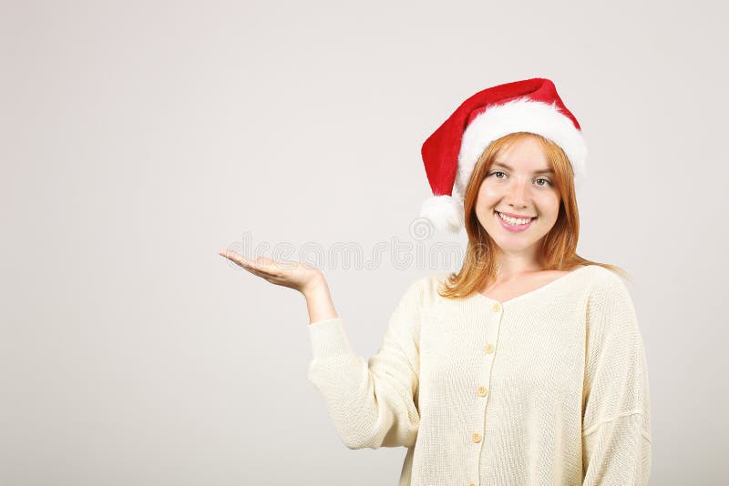 Chapeau de port femelle roux magnifique du ` s de Santa avec le bruit-pom, célébrant des vacances de fête de saison d'hiver images stock Chapeau de port femelle roux magnifique du ` s de Santa avec le bruit-pom, célébrant des vacances de fête de saison d'hiver images stock