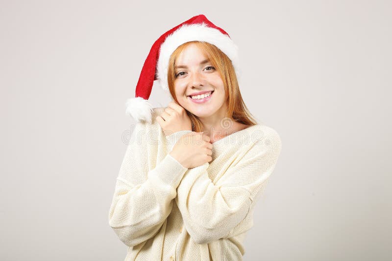 Chapeau de port femelle roux mignon du ` s de Santa avec le bruit-pom, célébrant des vacances de fête de saison d'hiver photographie stock Chapeau de port femelle roux mignon du ` s de Santa avec le bruit-pom, célébrant des vacances de fête de saison d'hiver photographie stock