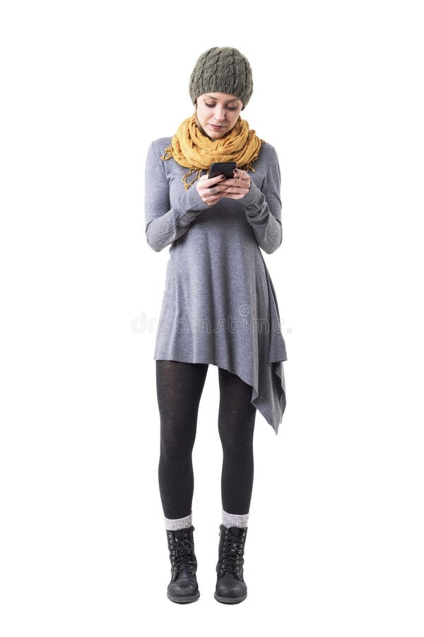 Chapeau de port de jeune femme mignonne sérieuse et message jaune de lecture de châle sur le téléphone portable photographie stock Chapeau de port de jeune femme mignonne sérieuse et message jaune de lecture de châle sur le téléphone portable photographie stock