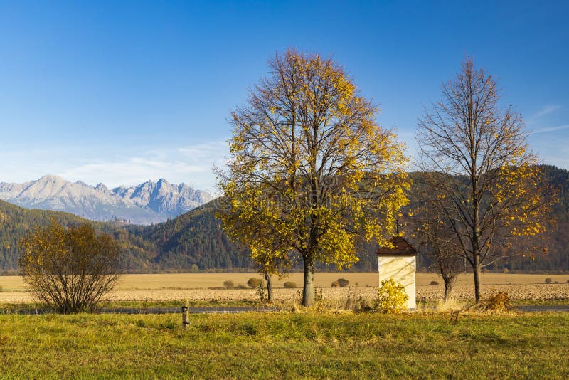 Kaplička se stromem v Nízkých Tatrách s pozadím Vysoké Tatry, Slovensko