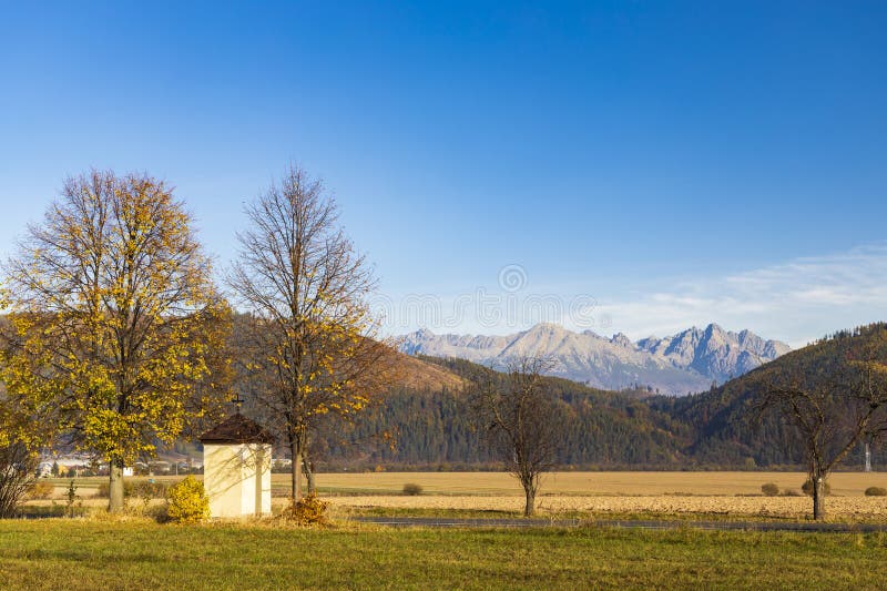 Kaplnka so stromom v Nízkych Tatrách s pozadím Vysoké Tatry, Slovensko