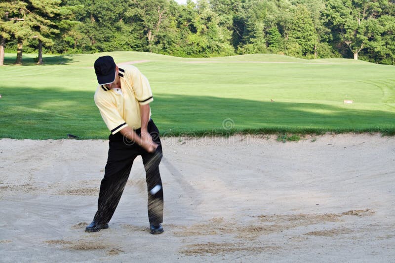 Man hitting out of sand trap. Sand flying and ball visible in front of pant leg. Man hitting out of sand trap. Sand flying and ball visible in front of pant leg.