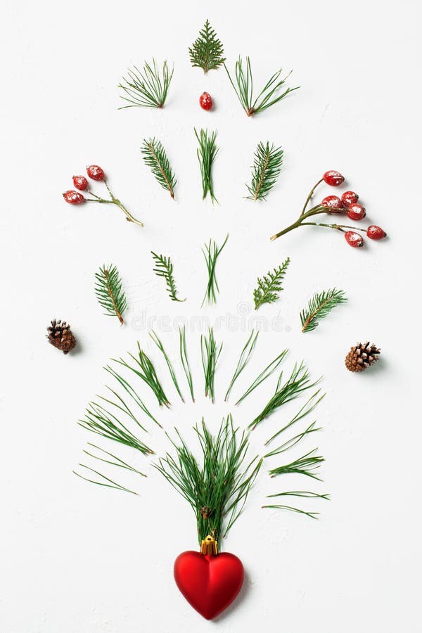 Winter firework splash of tree needles, cones and red berries from heart. Creative Valentine's Day concept, flat lay. Winter firework splash of tree needles, cones and red berries from heart. Creative Valentine's Day concept, flat lay.