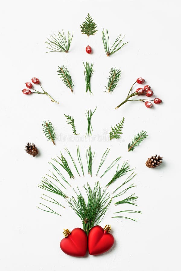Winter firework splash of tree needles, cones and red berries from two hearts. Creative Valentine's Day concept, flat lay. Winter firework splash of tree needles, cones and red berries from two hearts. Creative Valentine's Day concept, flat lay.