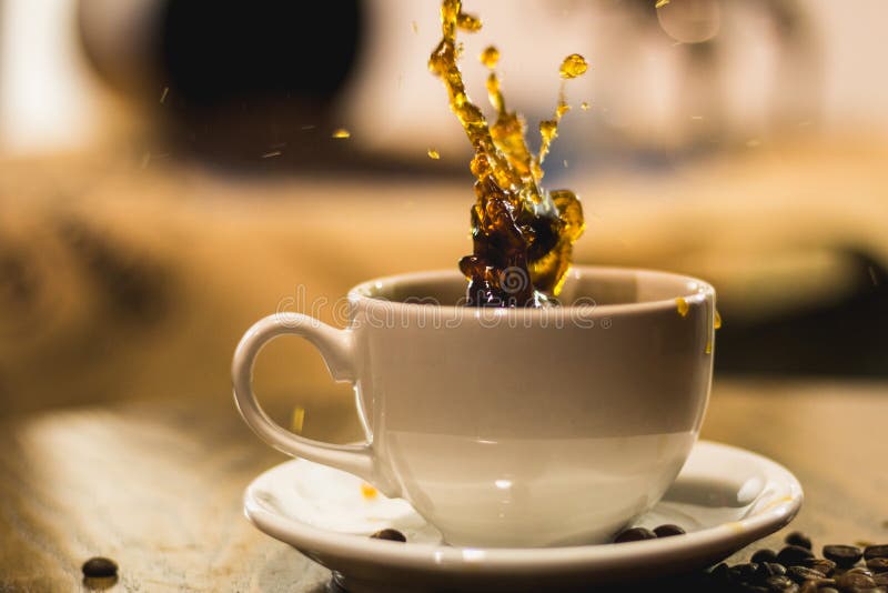 Chapoteo en un café en una taza blanca fotografía de archivo Chapoteo en un café en una taza blanca fotografía de archivo