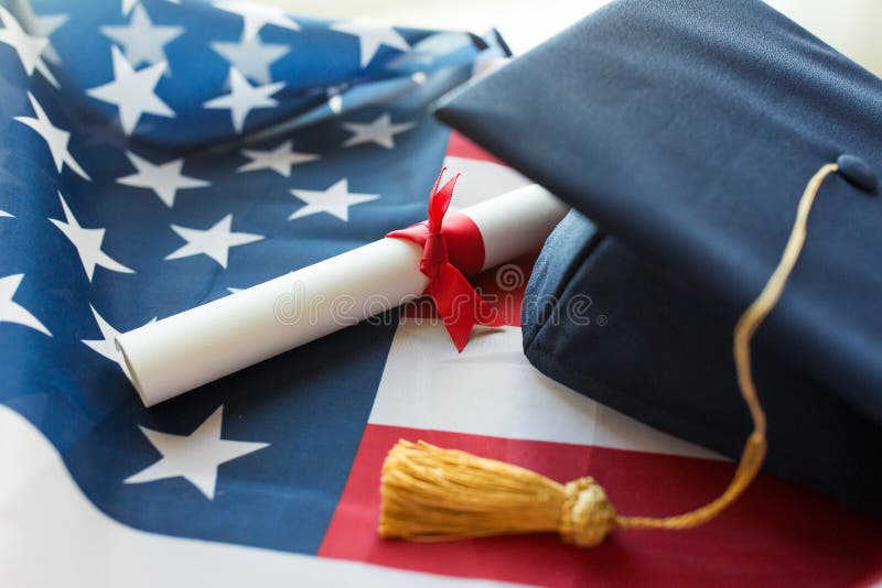 Education, graduation, patriotism and nationalism concept - close up of bachelor hat and diploma on american flag. Education, graduation, patriotism and nationalism concept - close up of bachelor hat and diploma on american flag