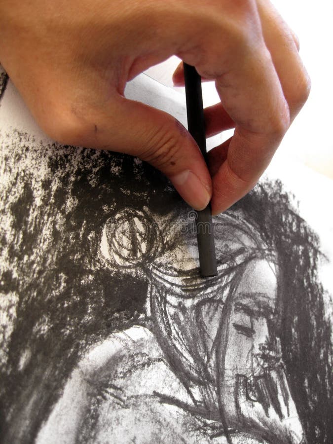 A hand using a charcoal stick to sketch a female figure. The sketch is of the photographerâ€™s original artwork. A hand using a charcoal stick to sketch a female figure. The sketch is of the photographerâ€™s original artwork