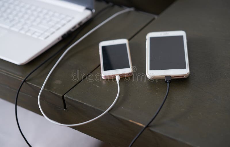Charger Line of Two Smart Phone on Wooden Table Surface for Energy