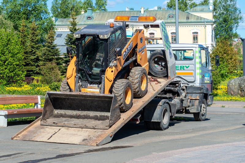 Petrozavodsk, Russia - 6 June 2022. Skid steer loader on a tow truck. tow truck with sliding platform. Petrozavodsk, Russia - 6 June 2022. Skid steer loader on a tow truck. tow truck with sliding platform