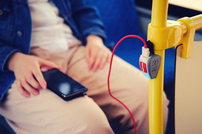 Charging a mobile phone in transport from a usb outlet. Man charges his phone while traveling on the bus