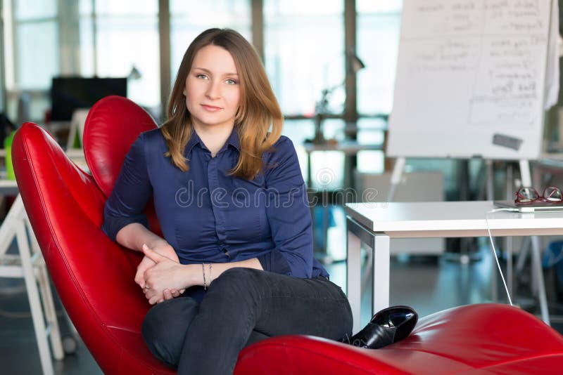 Charismatische Geschäfts-Person, die im roten Stuhl im modernen Büro sitzt lizenzfreie stockfotos Charismatische Geschäfts-Person, die im roten Stuhl im modernen Büro sitzt lizenzfreie stockfotos