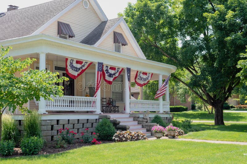 Charming home with cozy front portch decorated with American flags for the Fourth of July. Charming home with cozy front portch decorated with American flags for the Fourth of July