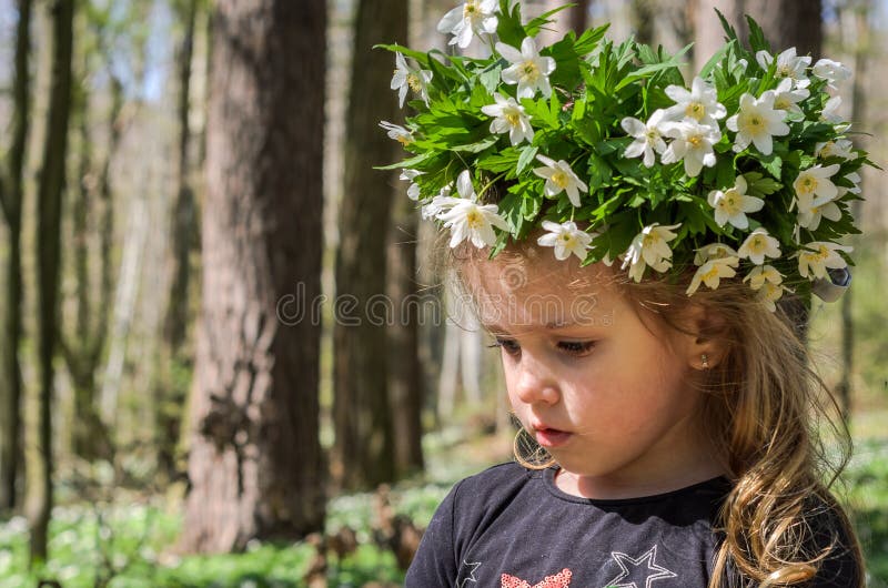 Charmant babymeisje met een kroon van witte bloemen op haar hoofd terwijl het lopen in het bos op een zonnige middag royalty-vrije stock afbeeldingen Charmant babymeisje met een kroon van witte bloemen op haar hoofd terwijl het lopen in het bos op een zonnige middag royalty-vrije stock afbeeldingen