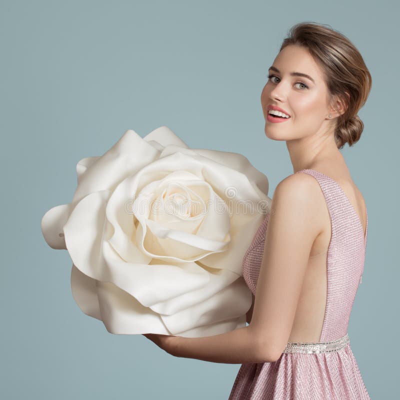 Charmante Frau, die eine riesige weiße Rose in den Händen hält lizenzfreies stockfoto