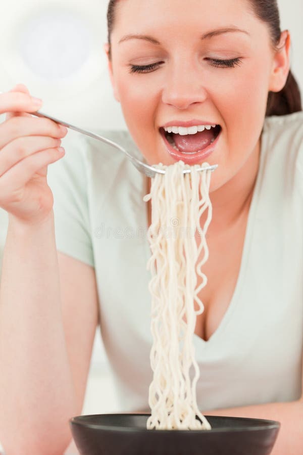Charmante vrouw die terwijl het eten van deegwaren stelt stock afbeelding Charmante vrouw die terwijl het eten van deegwaren stelt stock afbeelding