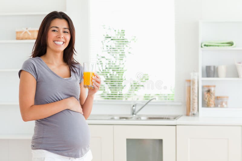 Charmig gravid kvinna som rymmer ett exponeringsglas arkivfoton Charmig gravid kvinna som rymmer ett exponeringsglas arkivfoton