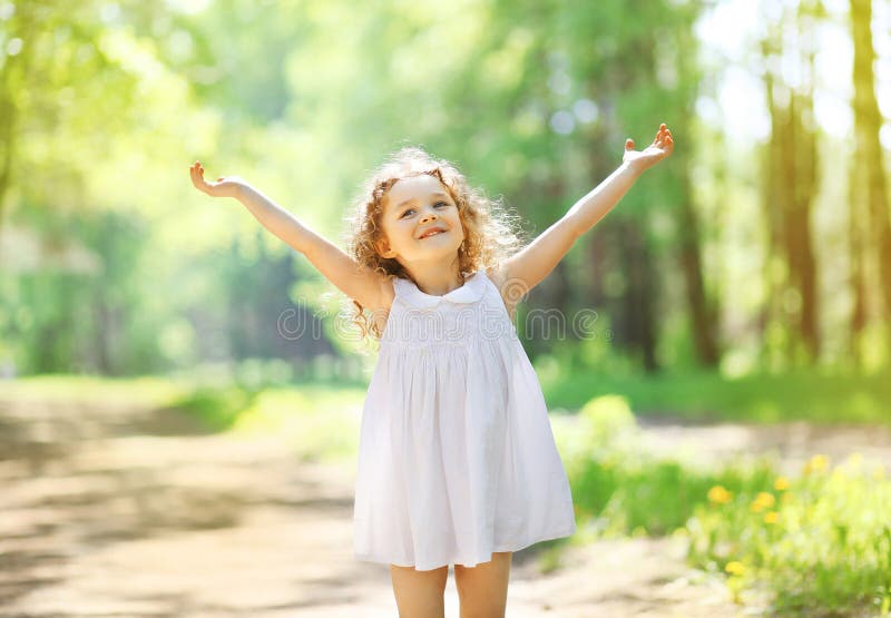 Charming little girl enjoying summer sunny day, raises his hands top, happy child. Charming little girl enjoying summer sunny day, raises his hands top, happy child