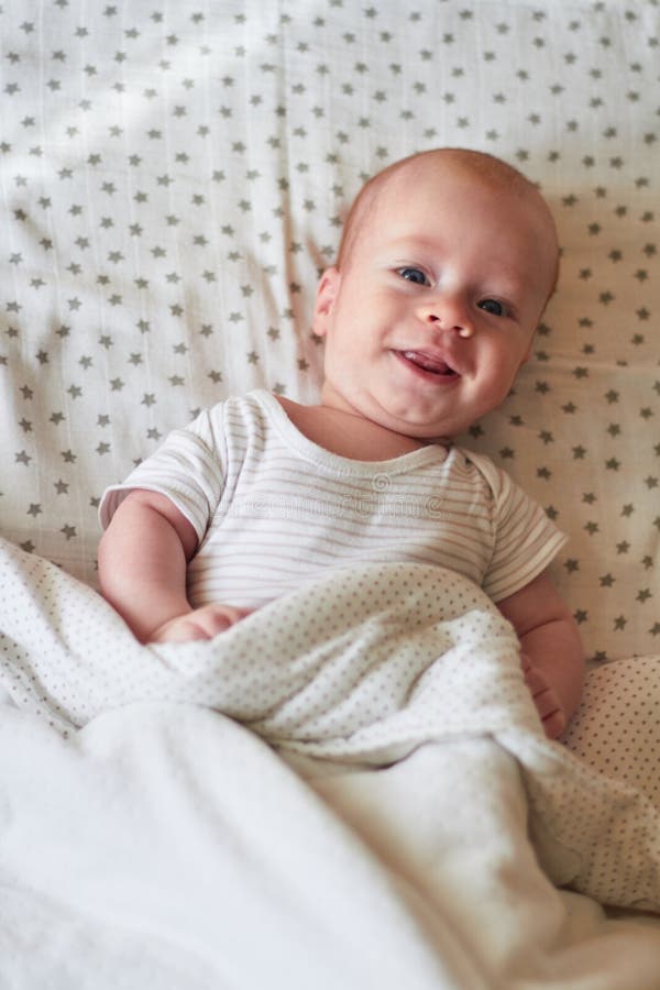 The Baby Smiles, Looking at the Camera, Lying in His Crib Stock Photo
