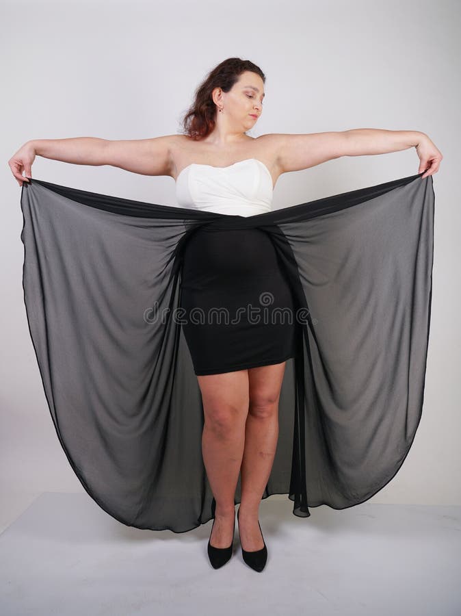 Charming chubby happy woman standing in flying evening dress on white studio background alone royalty free stock photo Charming chubby happy woman standing in flying evening dress on white studio background alone royalty free stock photo