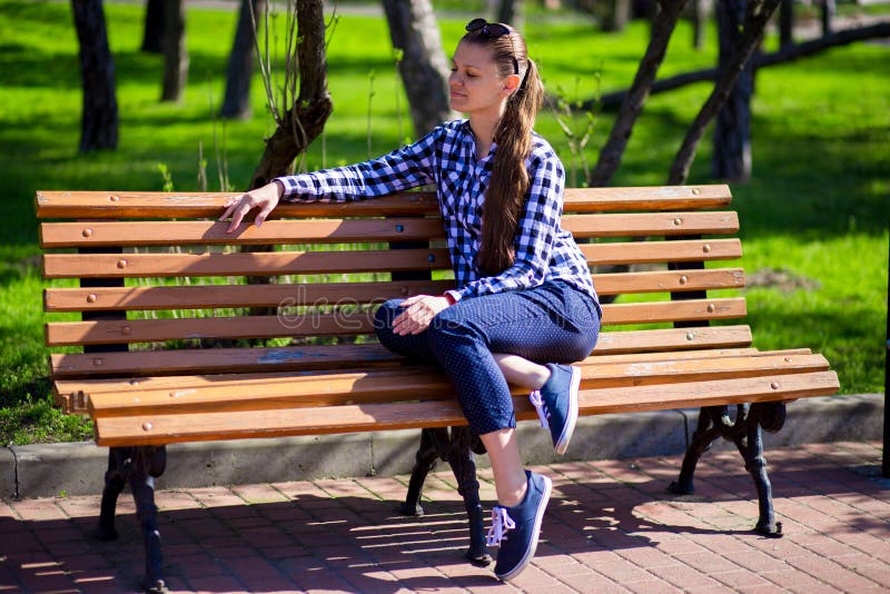 Charming girl walking in park and sits on bench with sunglasses stock photography Charming girl walking in park and sits on bench with sunglasses stock photography