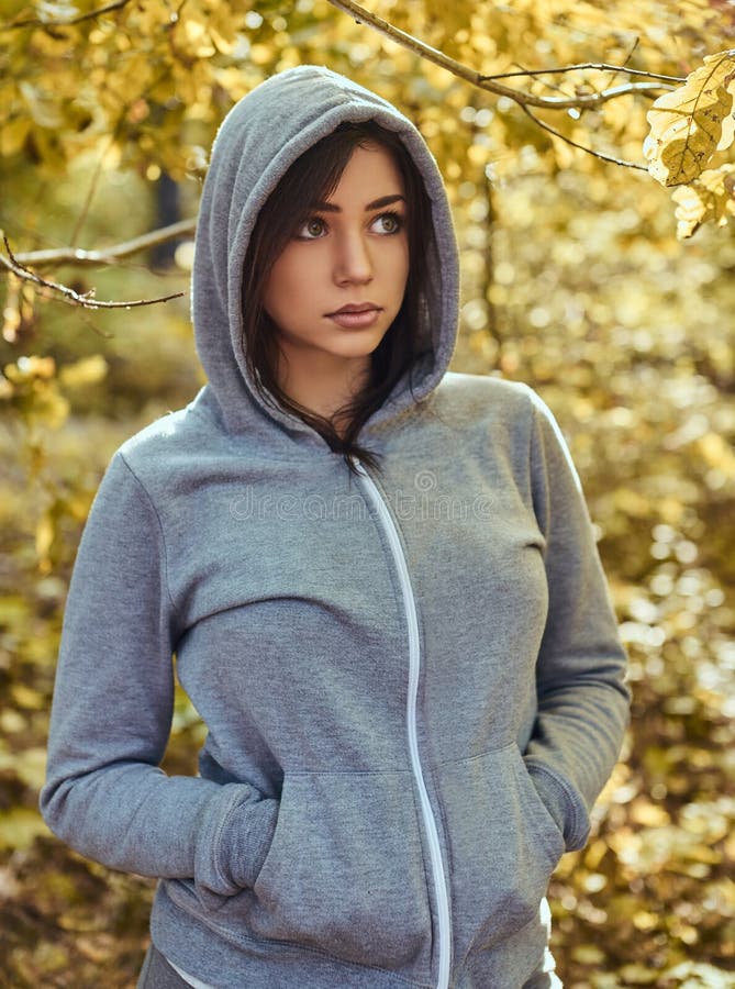 A charming girl wearing a gray hoodie in the autumn park. 