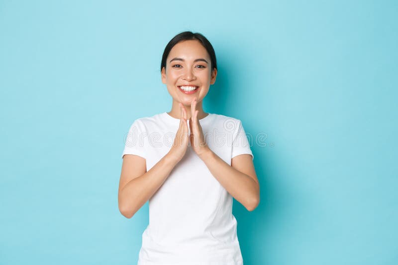 Charming happy asian female in white t-shrit smiling satisfied, clapping hands, congratulate person with win, praising