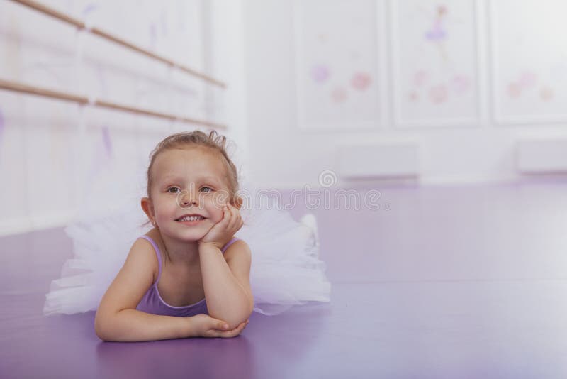 Cute little ballerina girl exercising at dance school