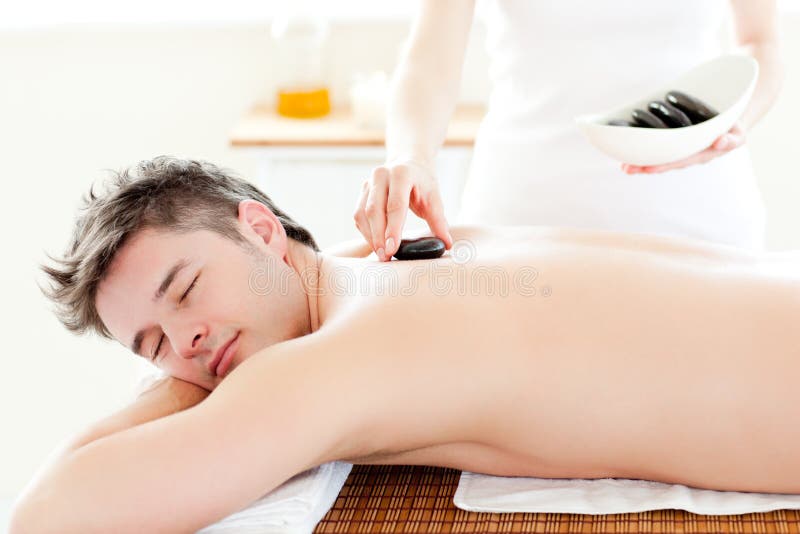 Charming man receiving a massage with hot stones stock image