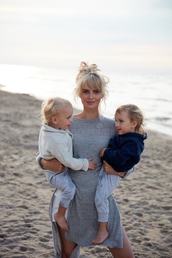 Charming mom carrying her beloved twin sons - summer shot