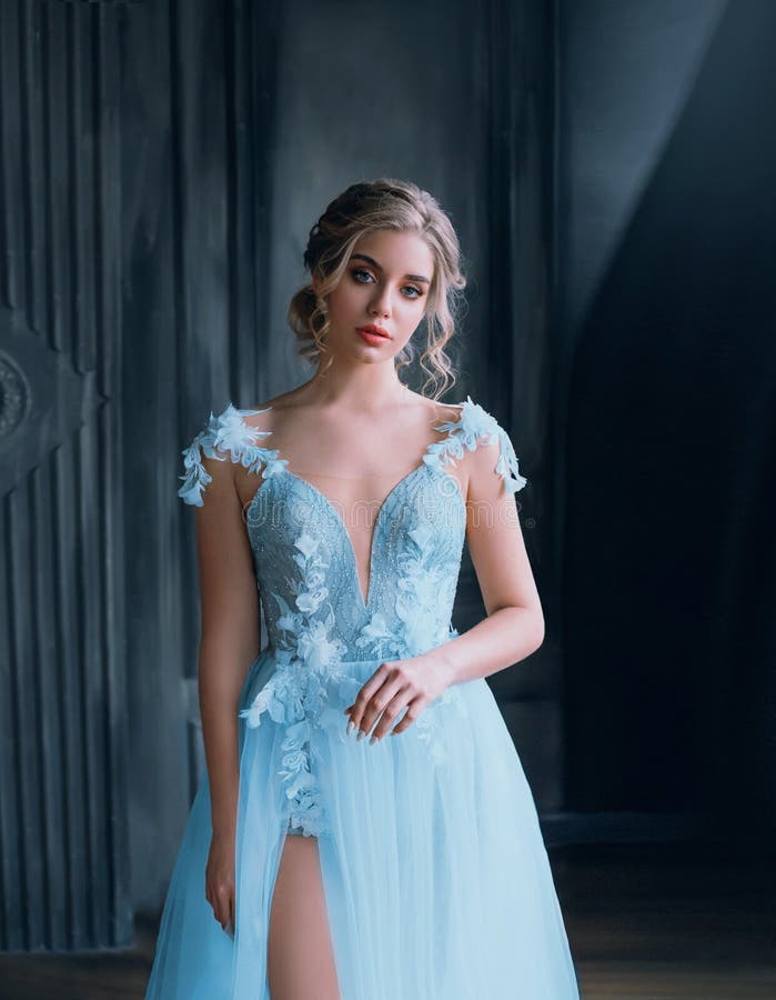 Charming pretty lady with a light fluffy blue dress, magnificent detailed gown tailoring, excellent work of a photographer and make-up artist, a princess costume with a bare leg in the cut