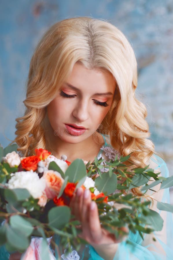 Charming young blond woman holding fresh flowers