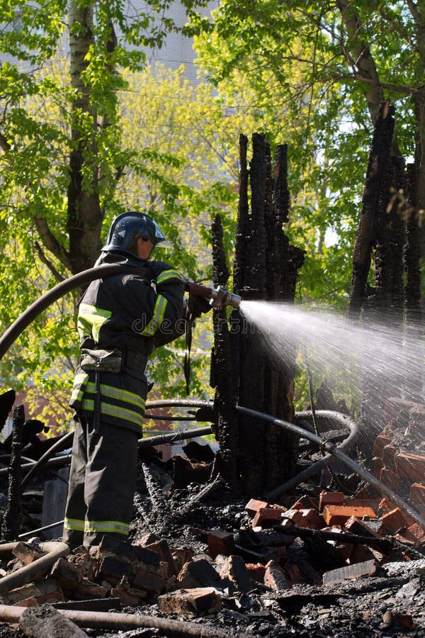 Fireman with hose extinguishing a fire in ruins. Fireman with hose extinguishing a fire in ruins