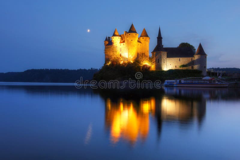 Chateau de Val v Auvergne, Francúzsko na twilight, s polmesiacom zrkadlenie v pokojných vodách umelé jazero, ktoré ju obklopujú.