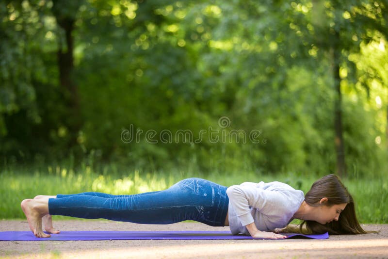 Chaturanga dandasana yoga pose in park alley