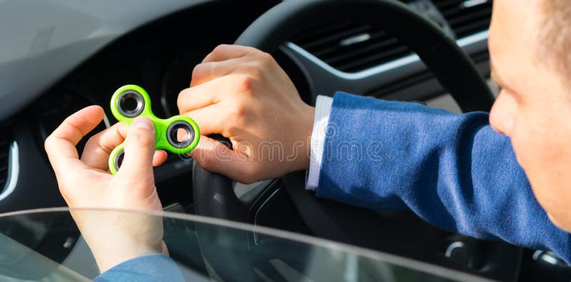 Chauffören av bilen rymmer en spinnare i hans hand, för att lugna royaltyfri fotografi Chauffören av bilen rymmer en spinnare i hans hand, för att lugna royaltyfri fotografi