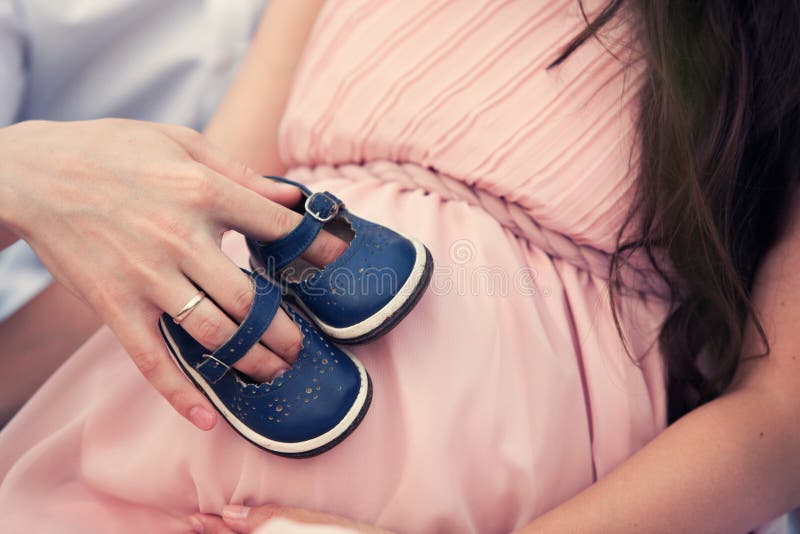 Chaussures de bébé sur son ventre photographie stock libre de droits Chaussures de bébé sur son ventre photographie stock libre de droits