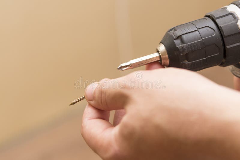 Chave de fenda sem fio nas mãos de um homem, o tema do trabalho do reparo fotos de stock Chave de fenda sem fio nas mãos de um homem, o tema do trabalho do reparo fotos de stock