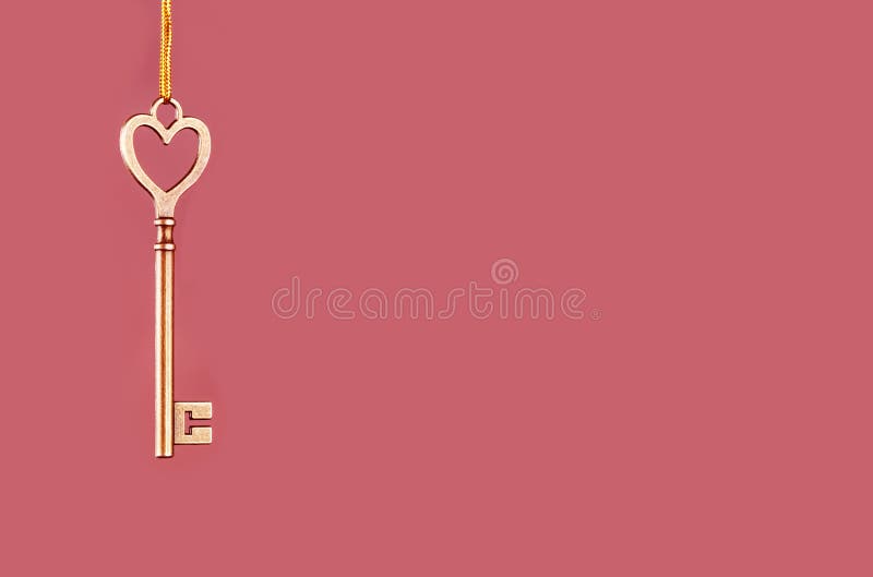 Chave dourada à suspensão em um fundo cor-de-rosa fotos de stock Chave dourada à suspensão em um fundo cor-de-rosa fotos de stock