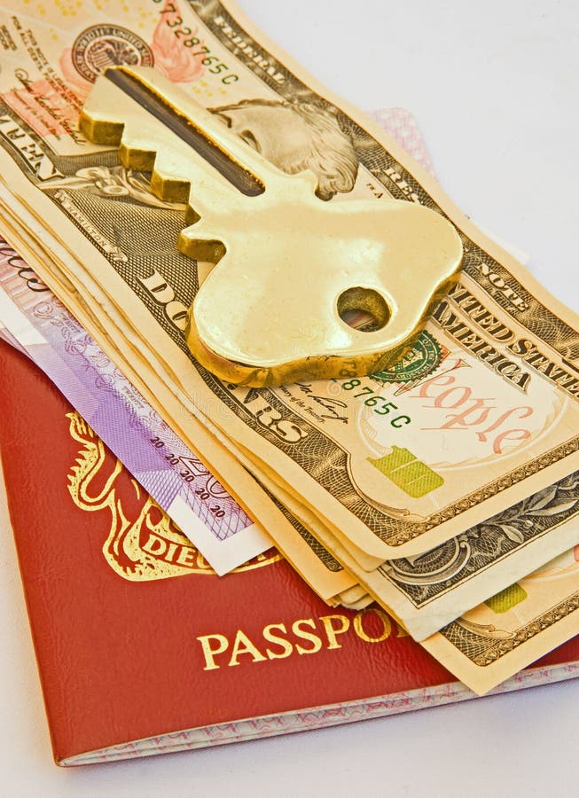 A large gold key lying on top of Dollar bills, Pounds and a passport. An abstract image of traveling light. A large gold key lying on top of Dollar bills, Pounds and a passport. An abstract image of traveling light.