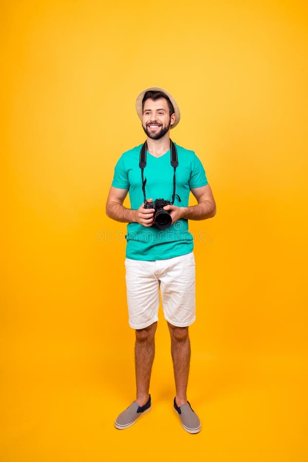 I want more adventures! Vertical full-length portrait of happy positive cheerful joyful handsome tourist with digital camera, wearing shorts and tshirt, isolated on vivid yellow background. I want more adventures! Vertical full-length portrait of happy positive cheerful joyful handsome tourist with digital camera, wearing shorts and tshirt, isolated on vivid yellow background