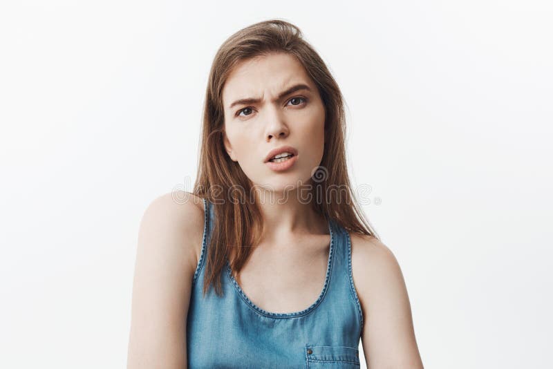 Che cosa vi ha fatto per dire la giovane bella ragazza mora dello studente in camicia blu che guarda in camera con medio ed aggre fotografia stock libera da diritti Che cosa vi ha fatto per dire la giovane bella ragazza mora dello studente in camicia blu che guarda in camera con medio ed aggre fotografia stock libera da diritti