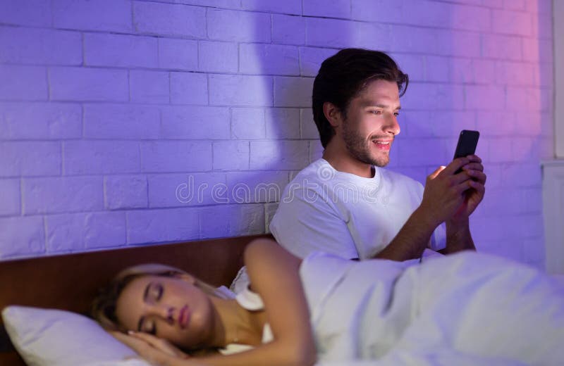 Cheating Boyfriend Texting On Cellphone While Girlfriend Sleeping In Bedroo...