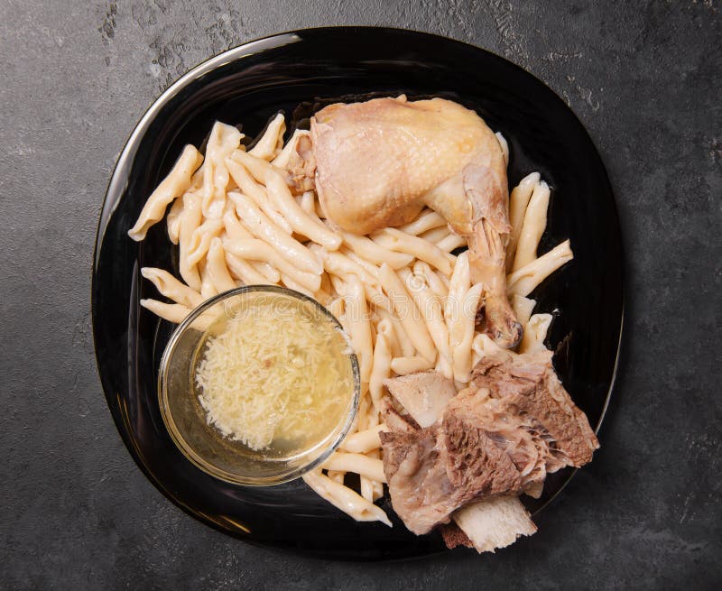 Chechen homemade dumplings with chicken and beef and garlic sauce in a plate on a black background