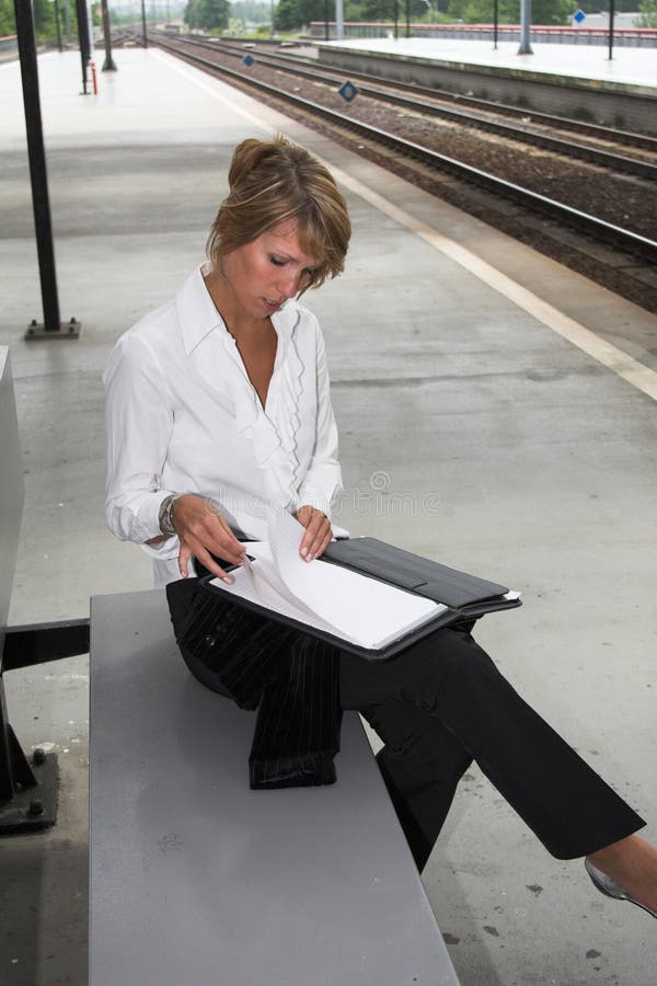 Bella bionda imprenditrice di controllo di note, mentre è in attesa del treno per arrivare.