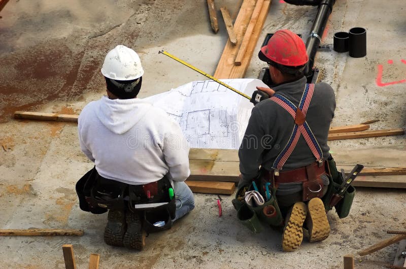 Dos hombres hojeada dibujo técnico durante construcción.