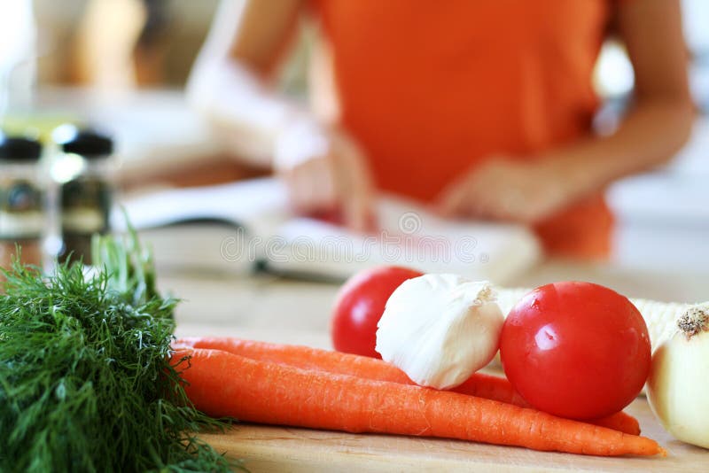 Žena v její kuchyni kontrola kuchařka pro recept a příprava čerstvé zeleniny k vaření.