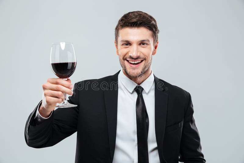 Cheeful young businessman smiling and drinking red wine